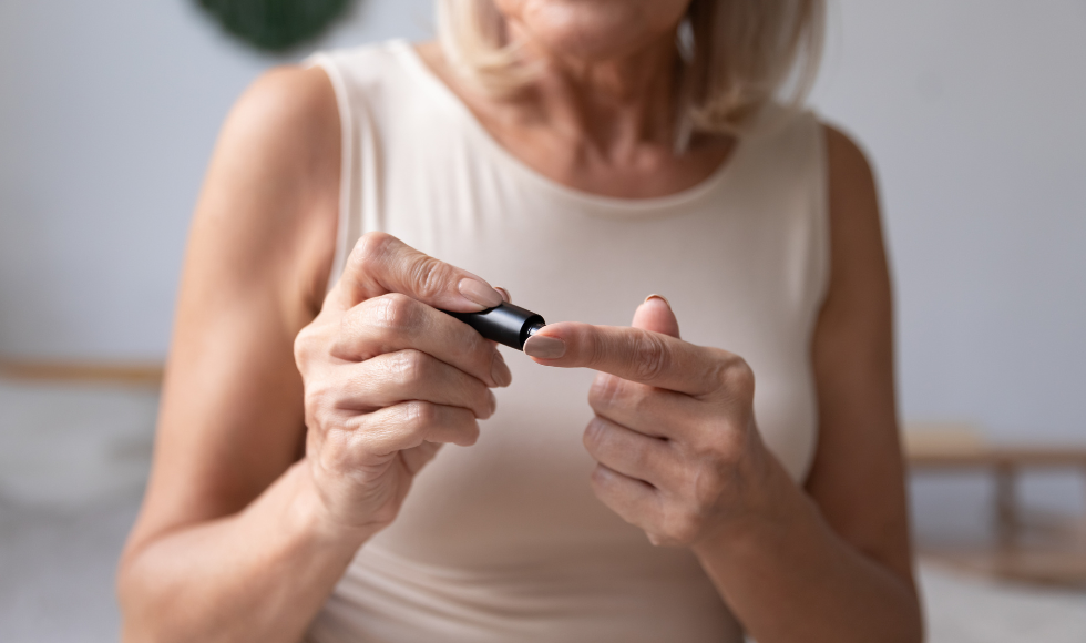 Older woman pricking her finger with a glucometer