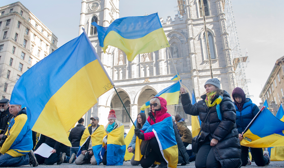 Protesters holding Ukrainian flags kneel outside a church