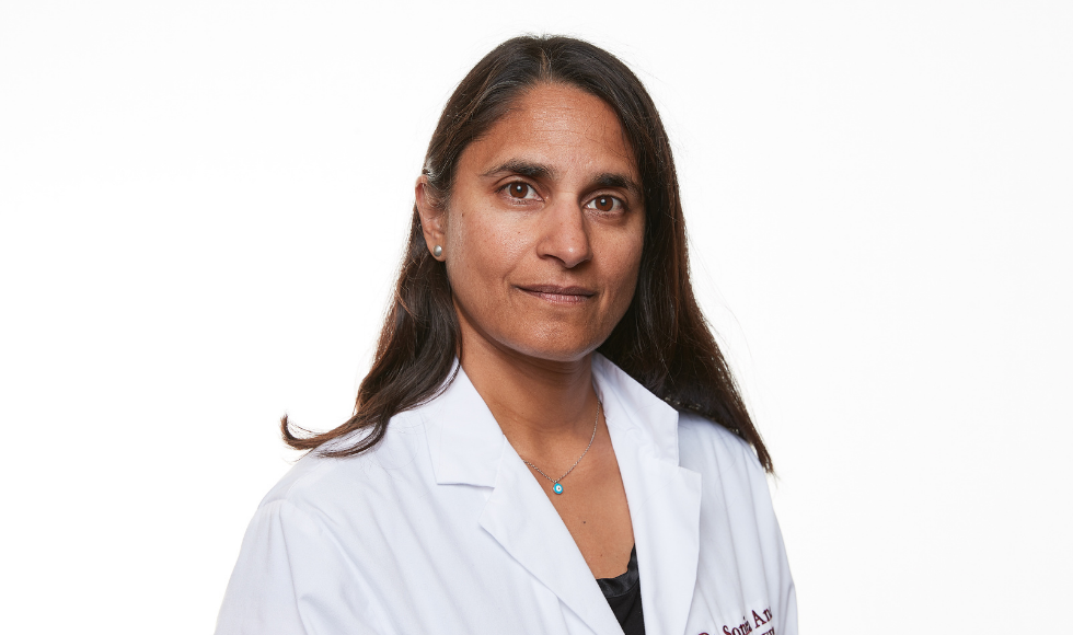 Sonia Anand wearing a white lab coat and looking directly at the camera