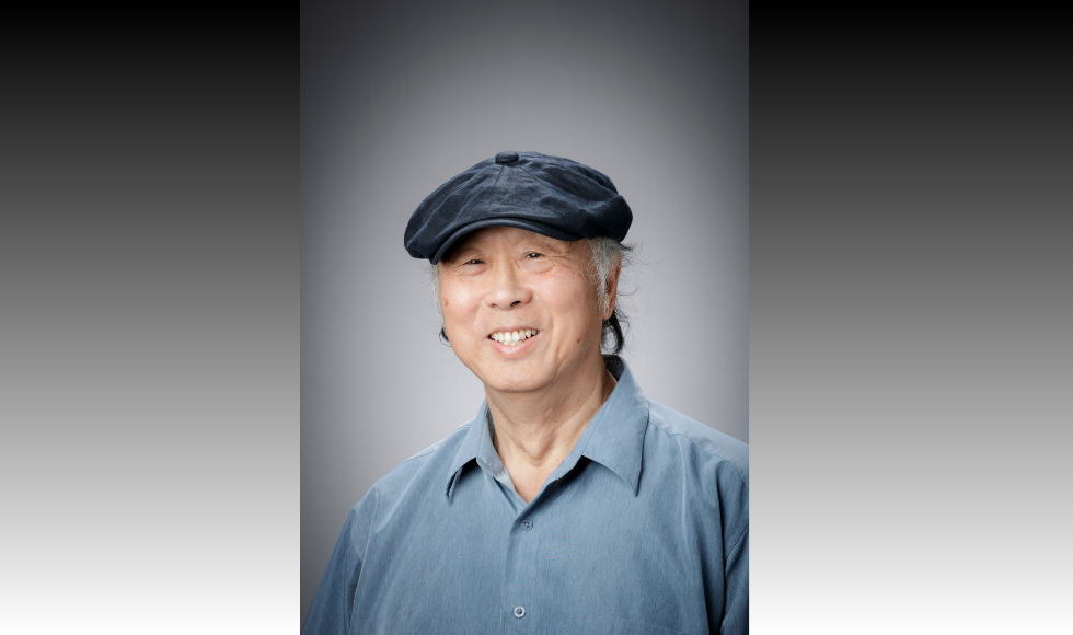 headshot of smiling Max Wong, wearing a collared shirt and a pageboy cap