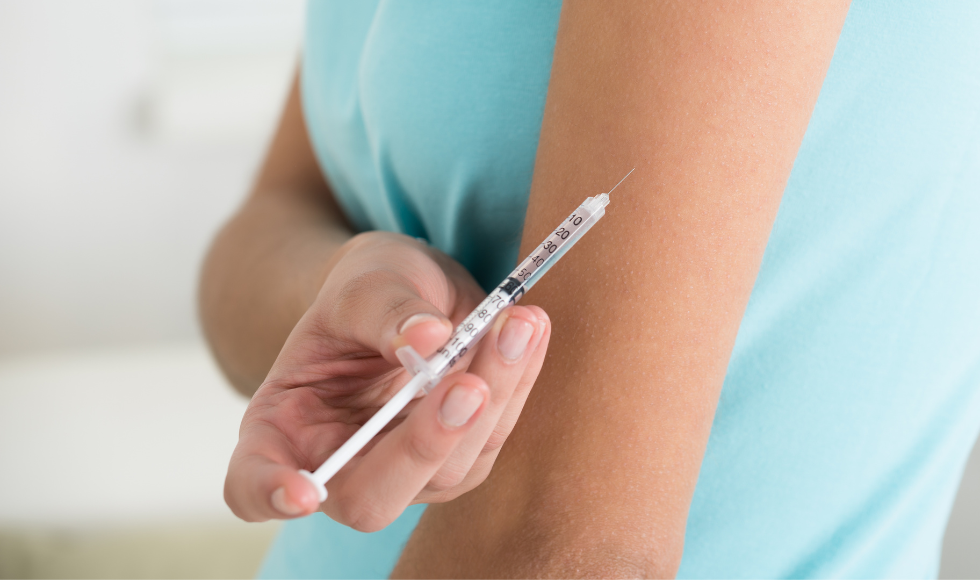 The midsection of a person giving themselves an insulin injection