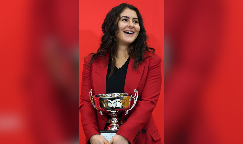 Athlete Bianca Andreescu in a red blazer and black top holding the Lou Marsh trophy.