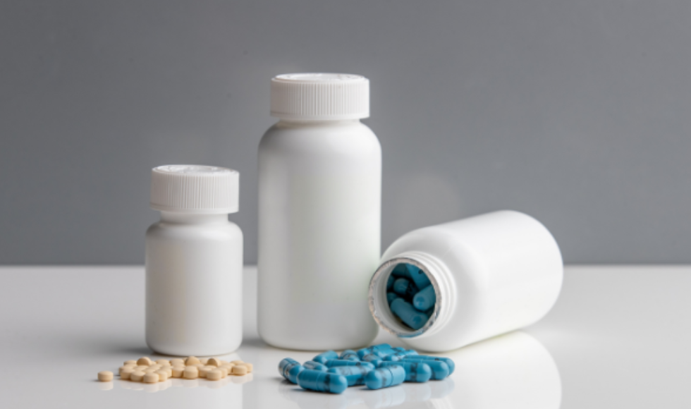 Three unlabelled pill bottles, some with beige pills and some with blue