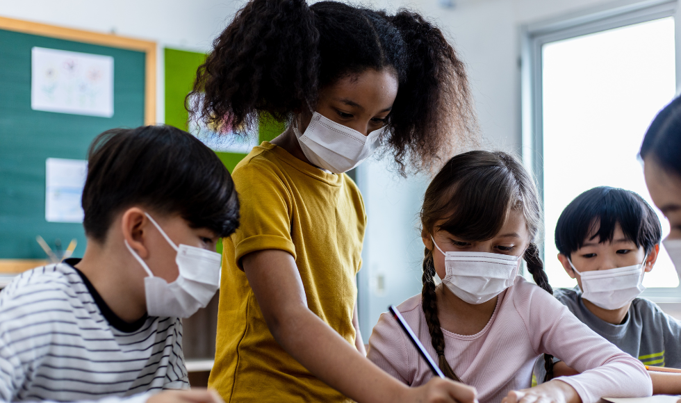 A group of school-age children wearing masks in the classrooml.