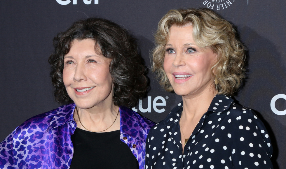 'Grace and Frankie' actresses Lily Tomlin and Jane Fonda posing for a photo against a dark blue backdrop