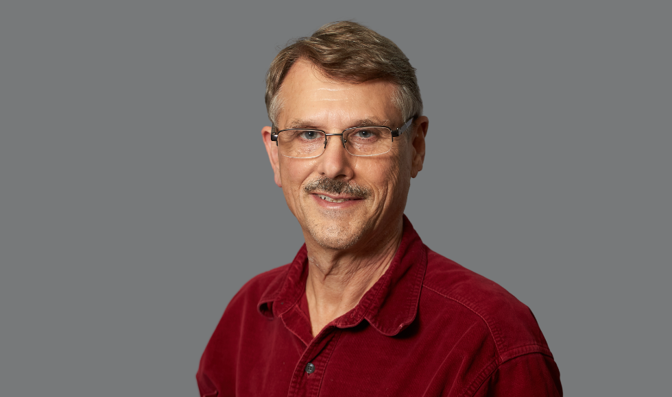 headshot of Gordon Guyatt in a red shirt against a grey backdrop.