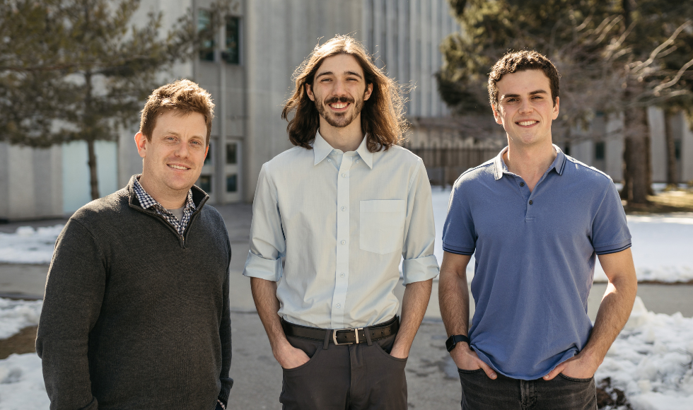 Three people standing outdoors smiling at the camera