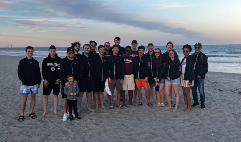 A group of people posing for a photo on a beach at dusk