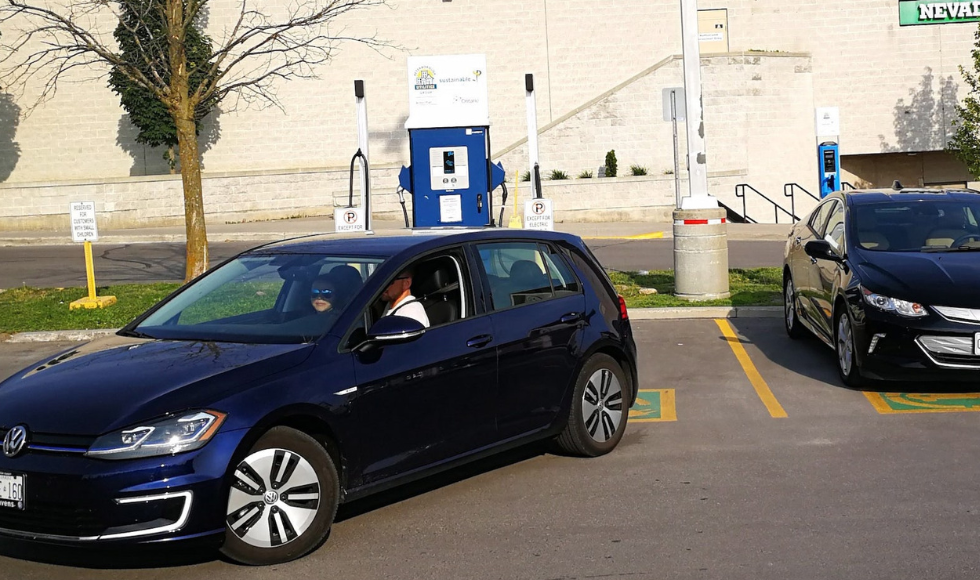 Volkswagen e-golf backing into an electric vehicle parking spot on a sunny day