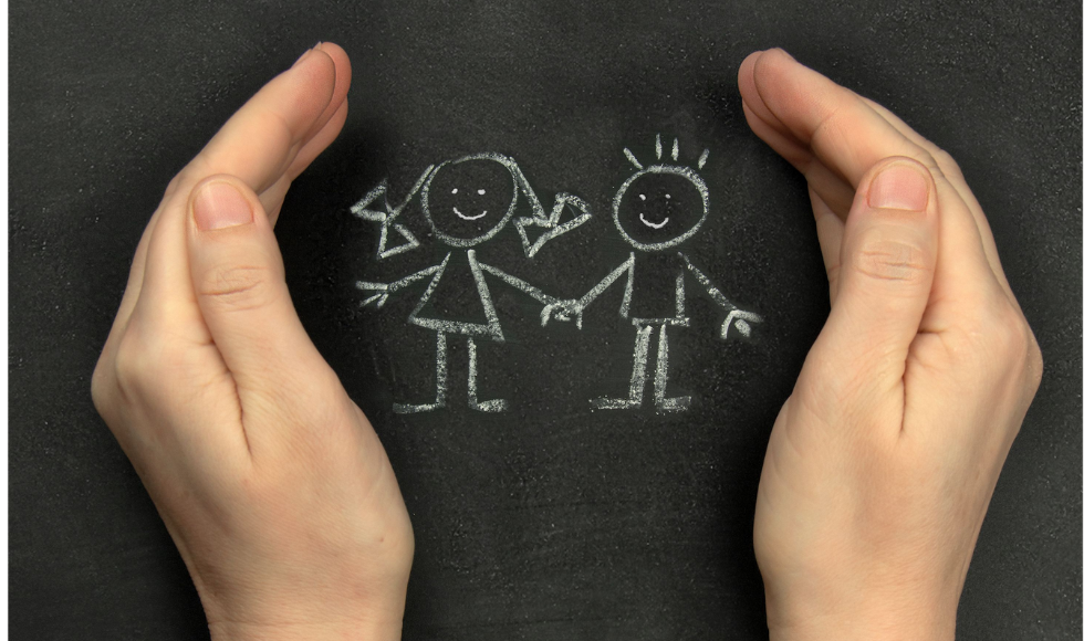 Close shot of adult hands cupped protectively around a chalk drawing of children