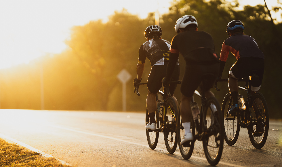 Three cyclists on a road in the early morning light