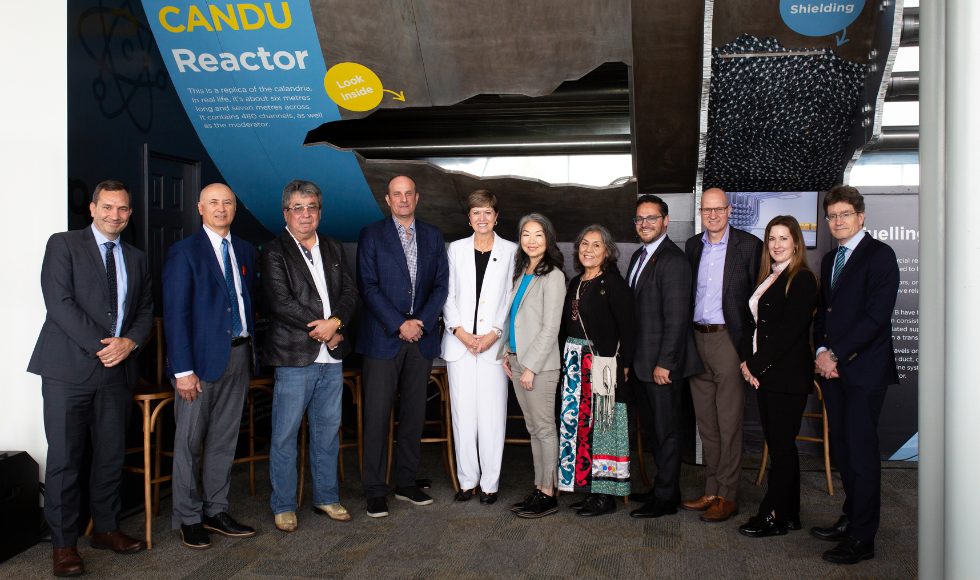 A group of people pose for a photo in front of a sign that reads, 'CANDU Reactor'