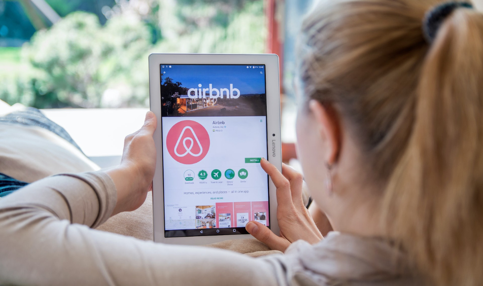 A person using Airbnb on a tablet, seen from behind.