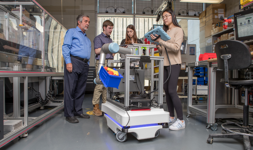 A professor and three students in an advanced manufacturing technology lab