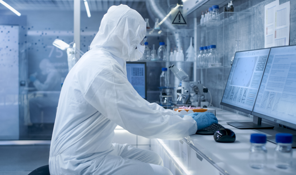Person in full protective gear, working in a lab setting.