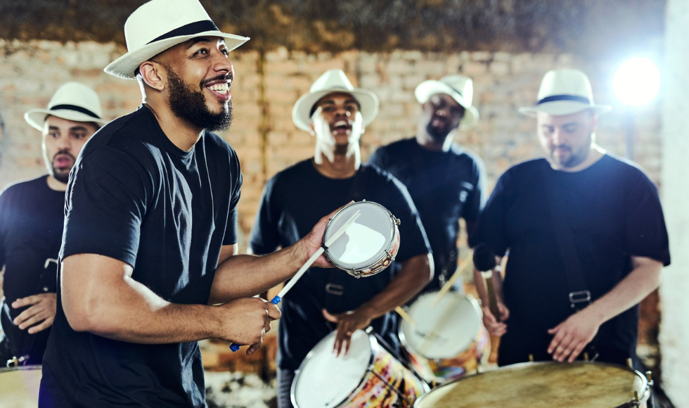 A group of people in fedoras and matching clothes playing percussion instruments