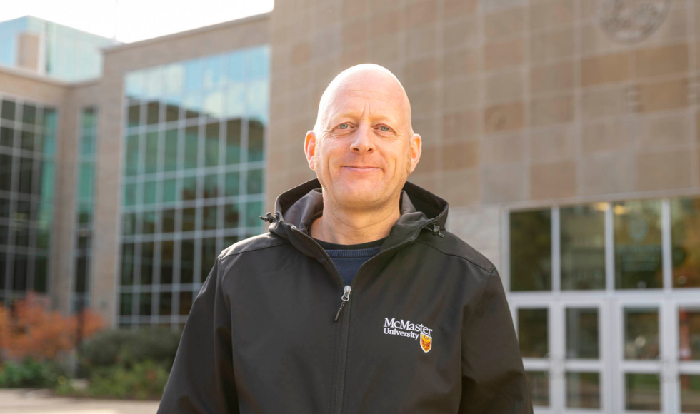 Niko Hildebrandt standing outdoors wearing a McMaster University branded jacket