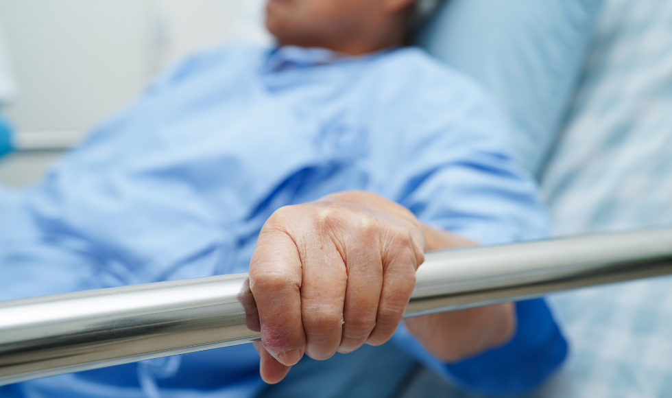 Image of a person holding onto a hospital bed