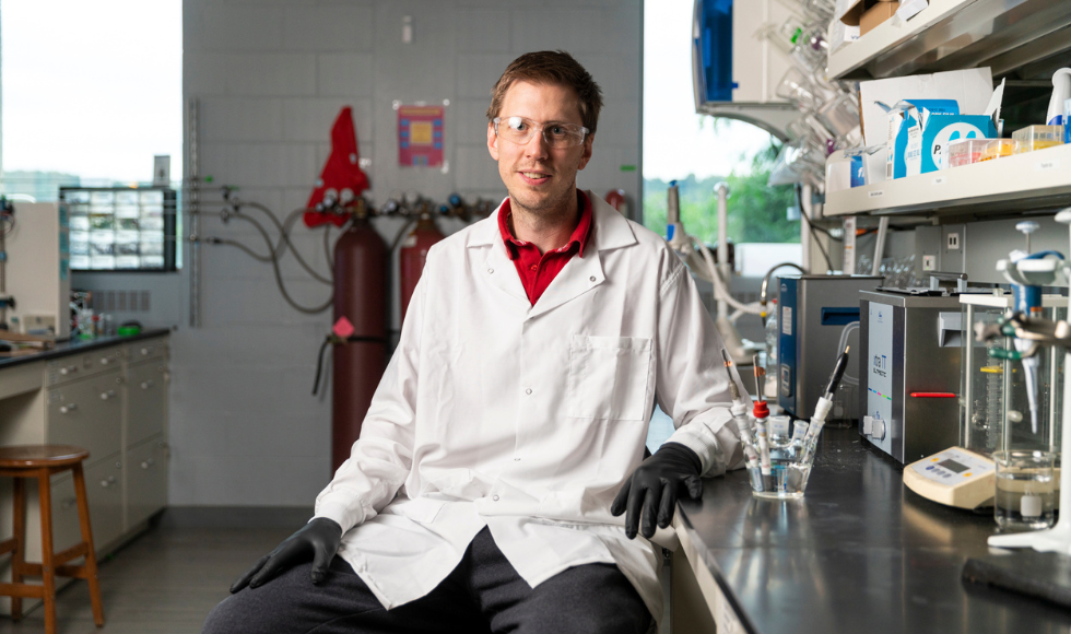 Image of Drew Higgins in his lab smiling for a photo