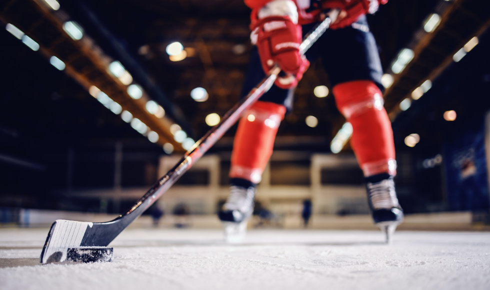 Blurry image of a hockey player with his stick on the ice using the puck