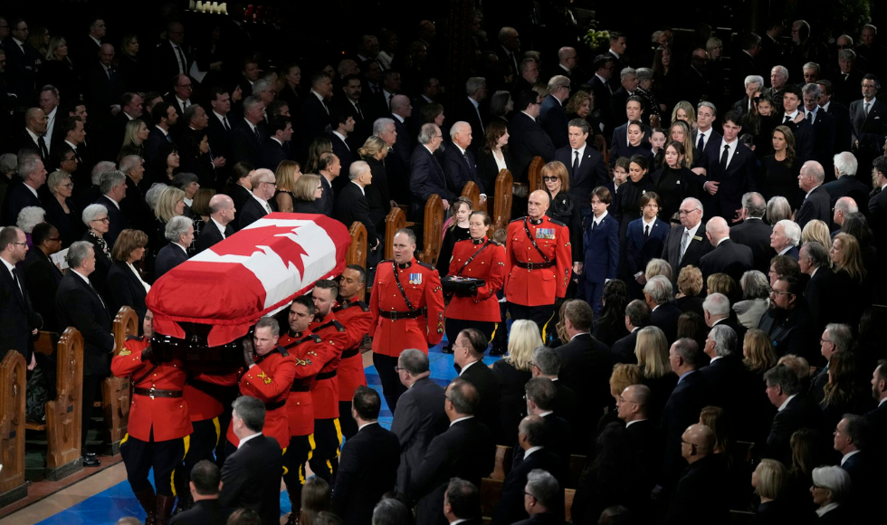 RCMP pallbearers carry a casket in a crowded church.