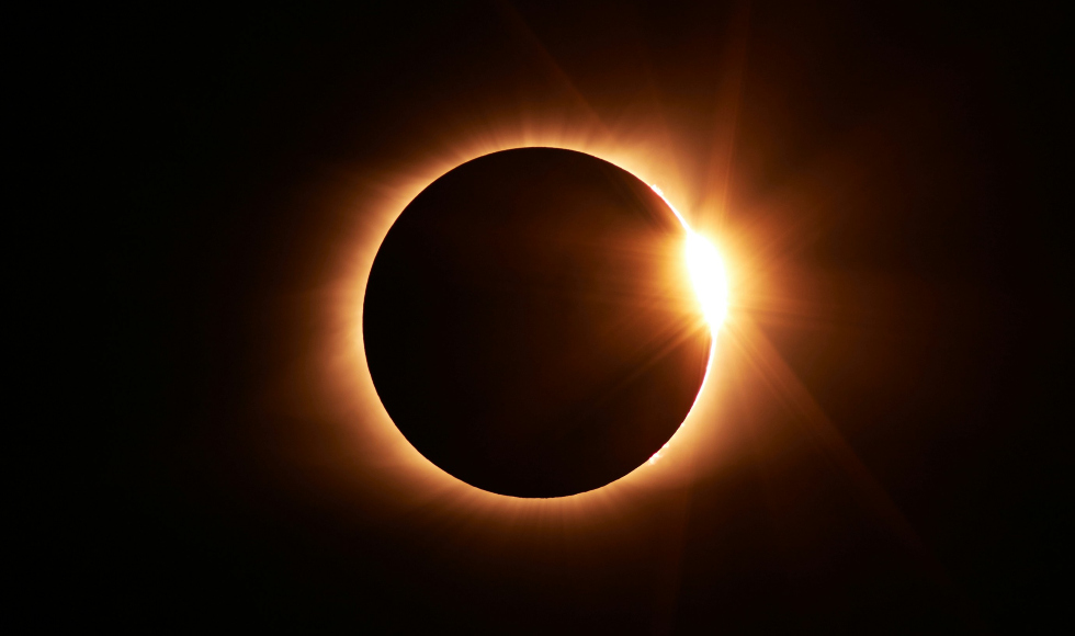 Total solar eclipse, with a thin ring of orange around a dark circle in a dark sky