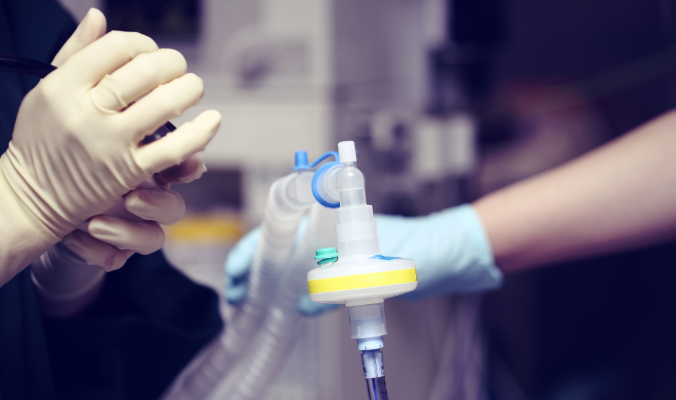 A ventilator tube is being held by a healthcare worker in a critical care unit.