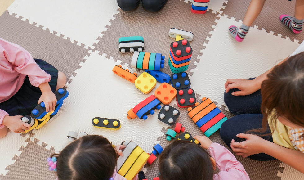 Seen from above, a foam floor on which children play with toys.