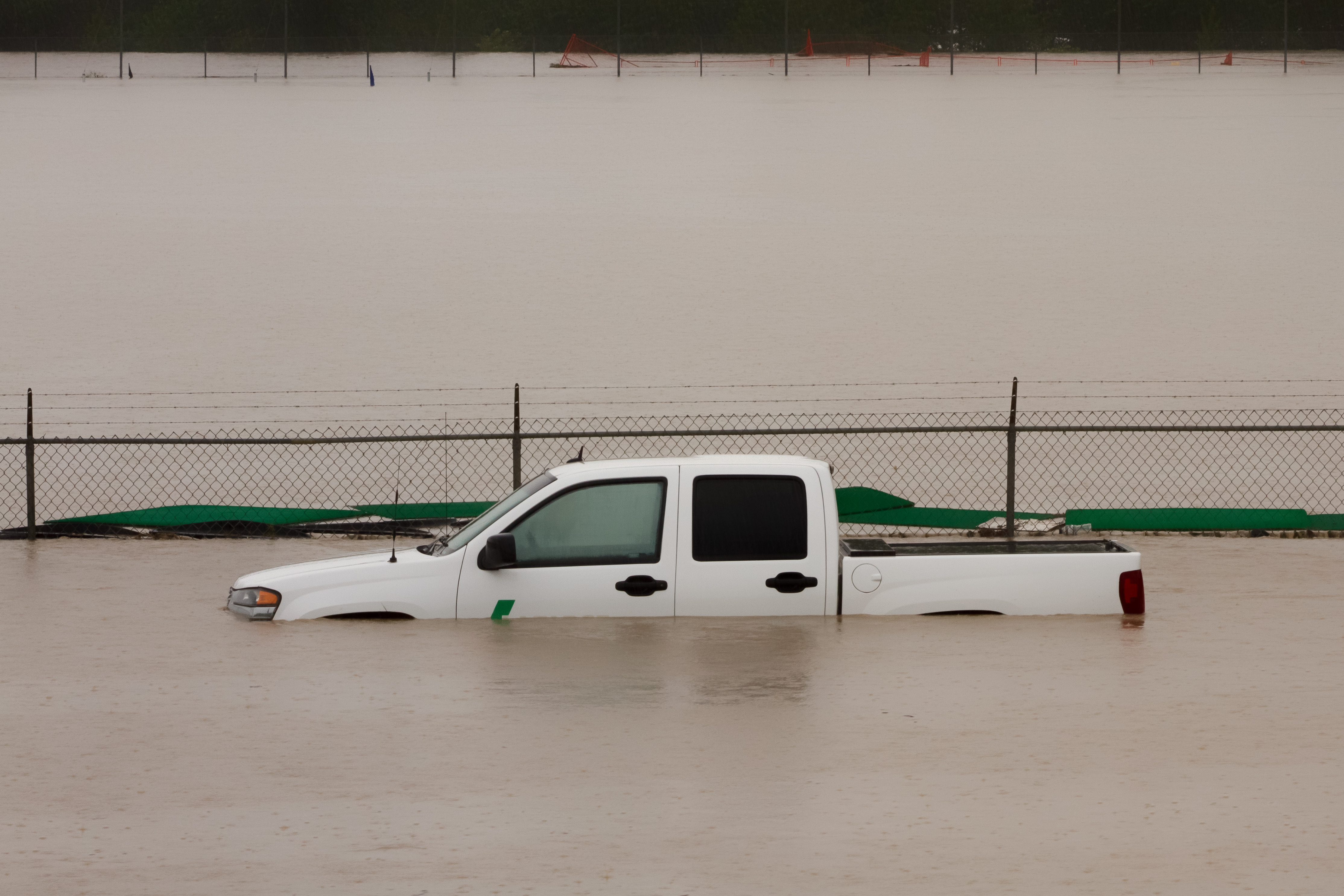 White pickup truck submerged in flood waters that come up to the door handles.