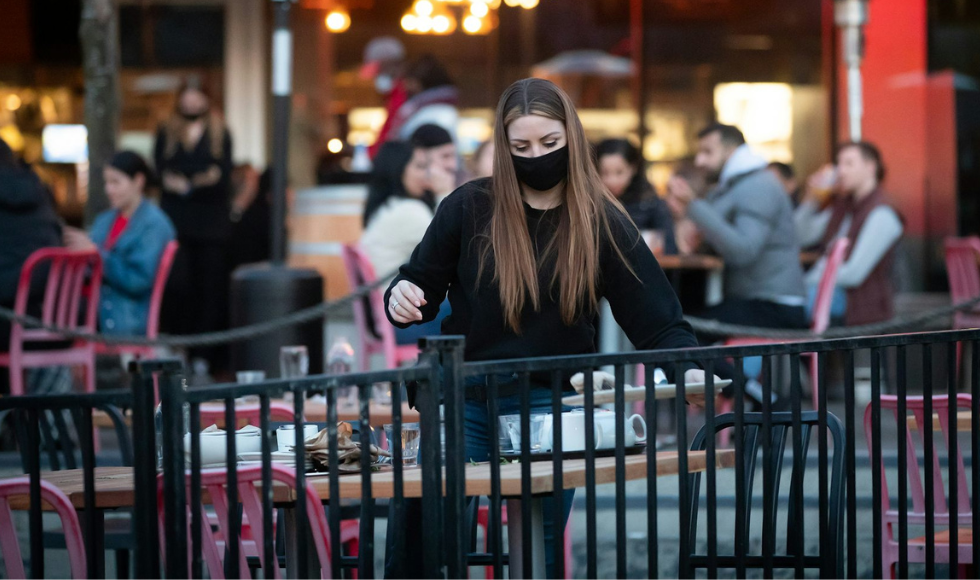 A server clears an outdoor restaurant table.