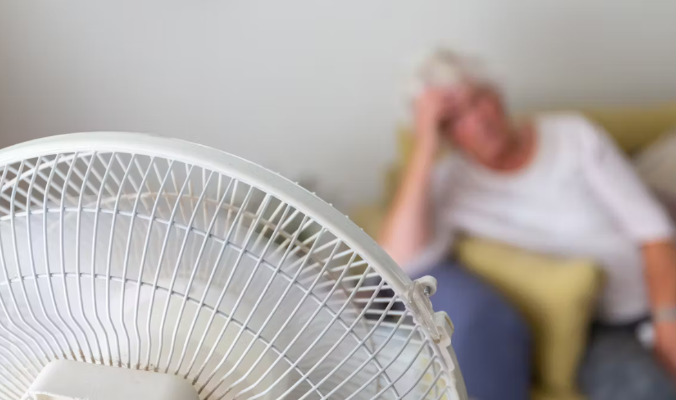 A senior sitting in front of a fan