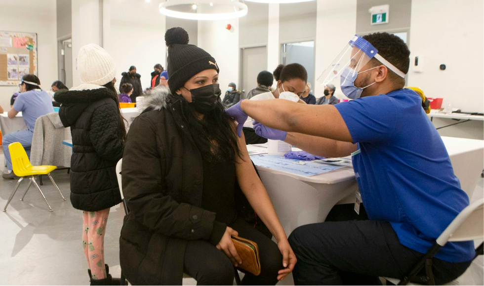 A person in winter clothing and a covid mask gets a vaccination at a covid vaccination clinic.