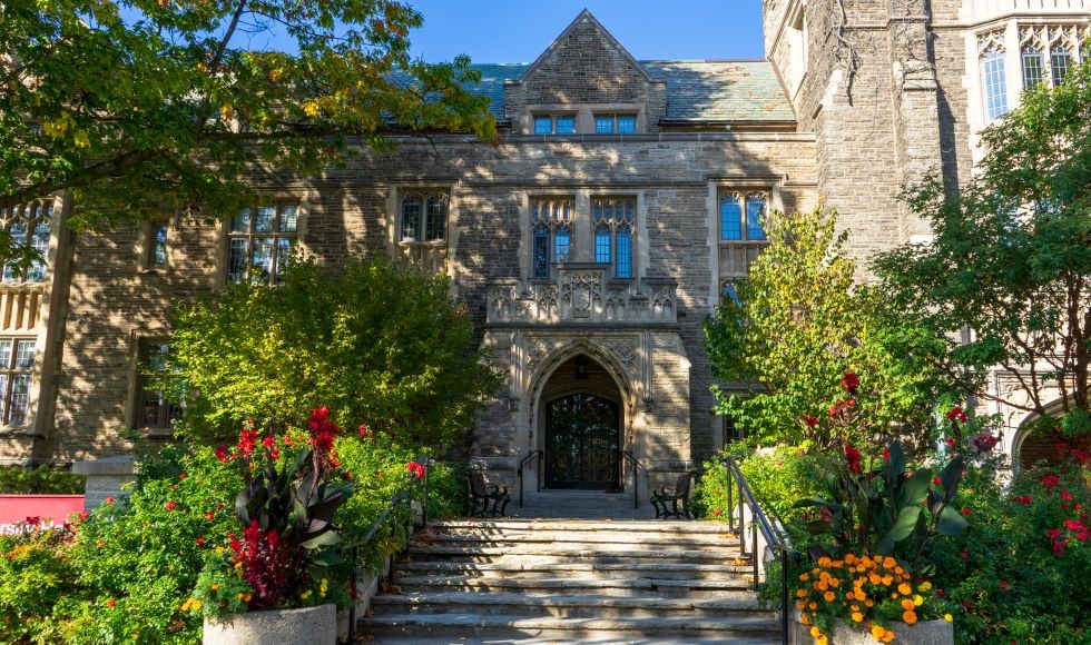 The front of University Hall framed by flowers and trees in the summer.