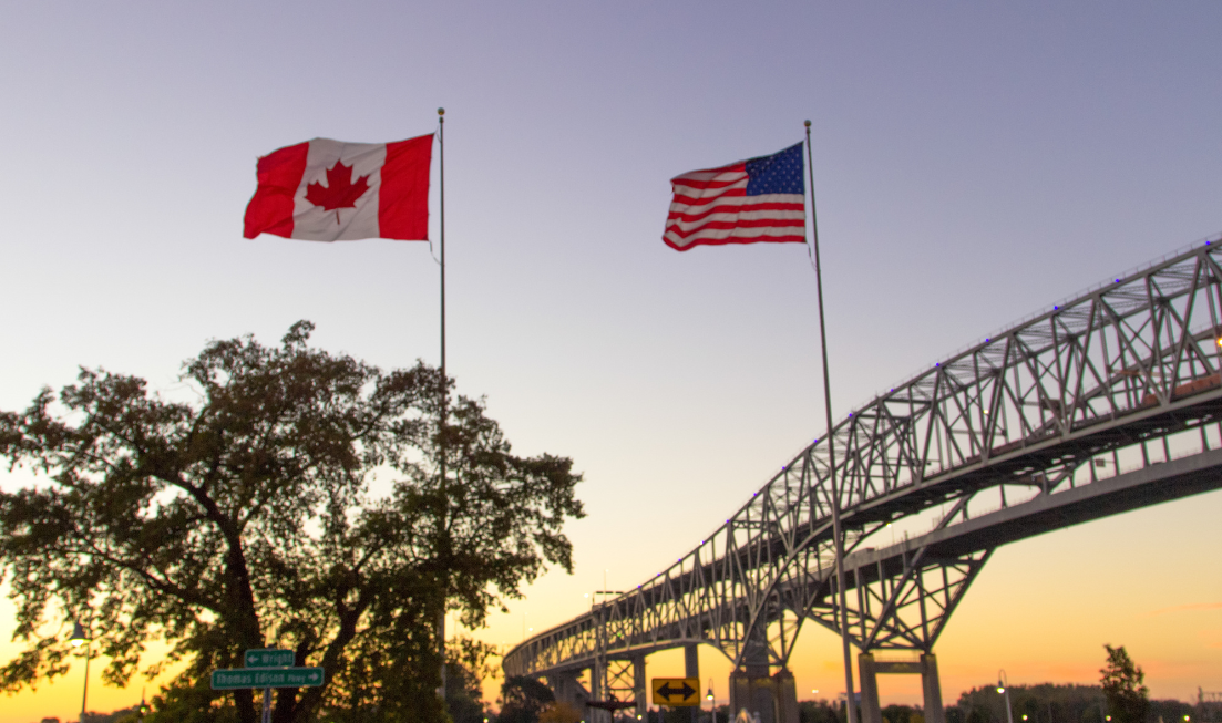 Canadian and American flags fly at sunset at the border crossing at the Blue Water Bridge.