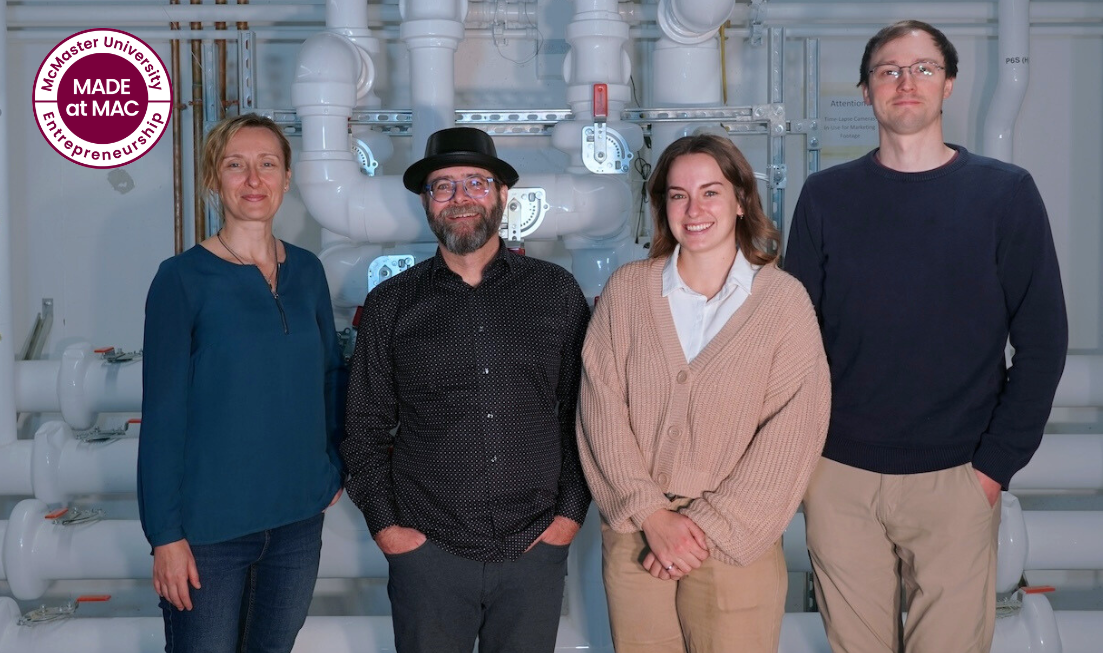 Four smiling people stand against a backdrop of heat and water pipes. There's a made and mac logo in the top left corner.