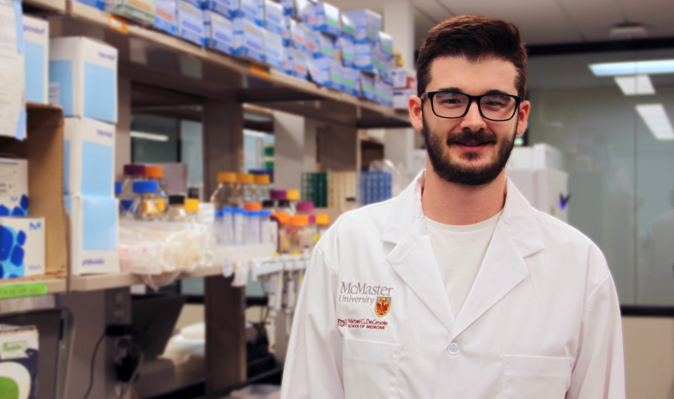 Stephen Garrett wearing a white lab coat and smiling directly at the camera while standing in a laboratory setting