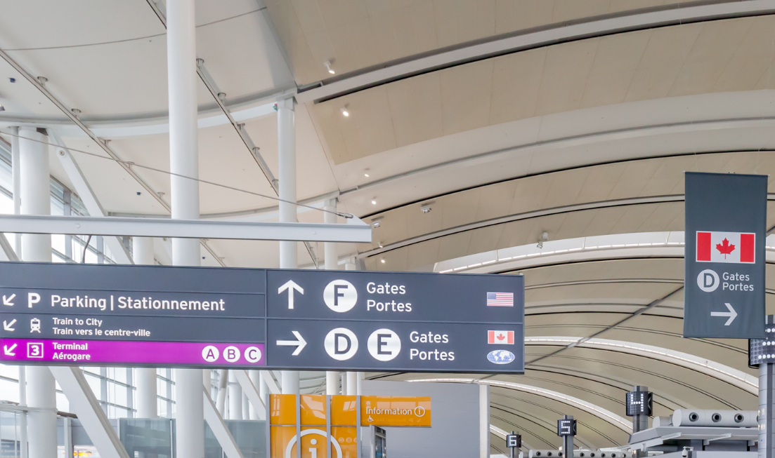 Signs at a Canadian airport directing people toward departure gates for the U.S. and for Canadian destinations.