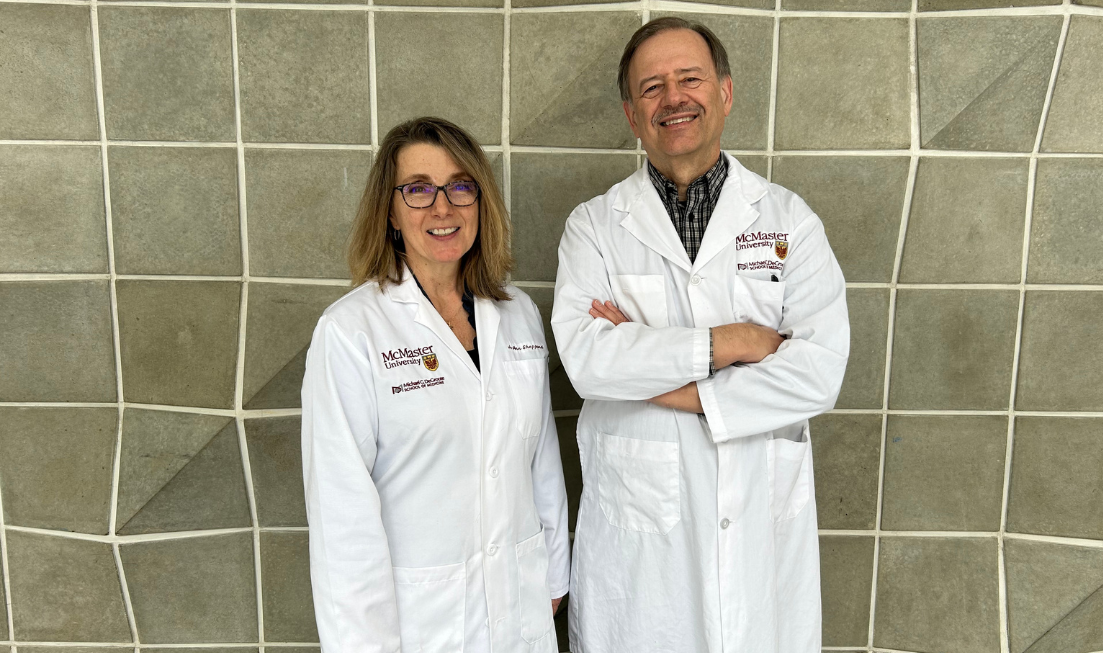 Two people in McMaster lab coats standing side by side, smiling.