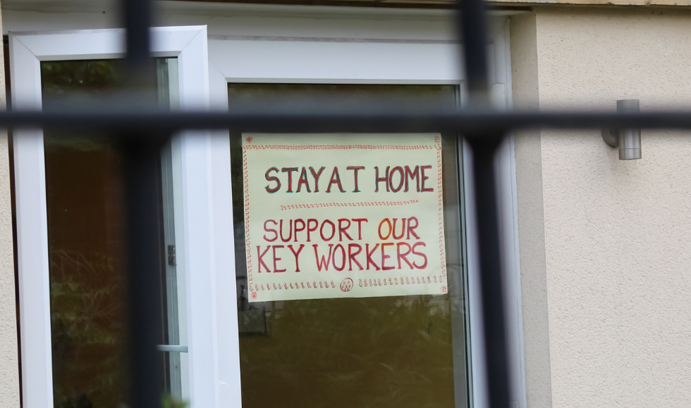 A sign in a window says 'Stay at Home. Support our key workers.'