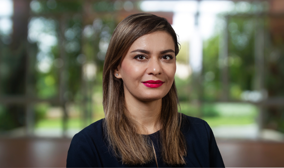 head and shoulders of Maryam Ghasemaghaei, wearing a dark top against a soft focus backdrop of greenery.