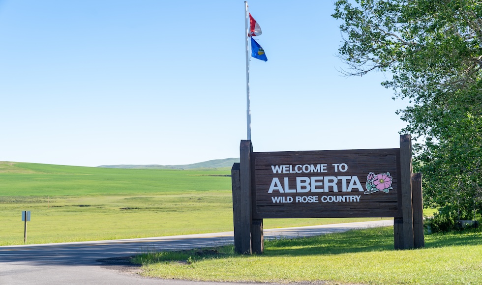 A large sign on the sign of a road reads 'Welcome to Alberta, Wild Rose Country.'