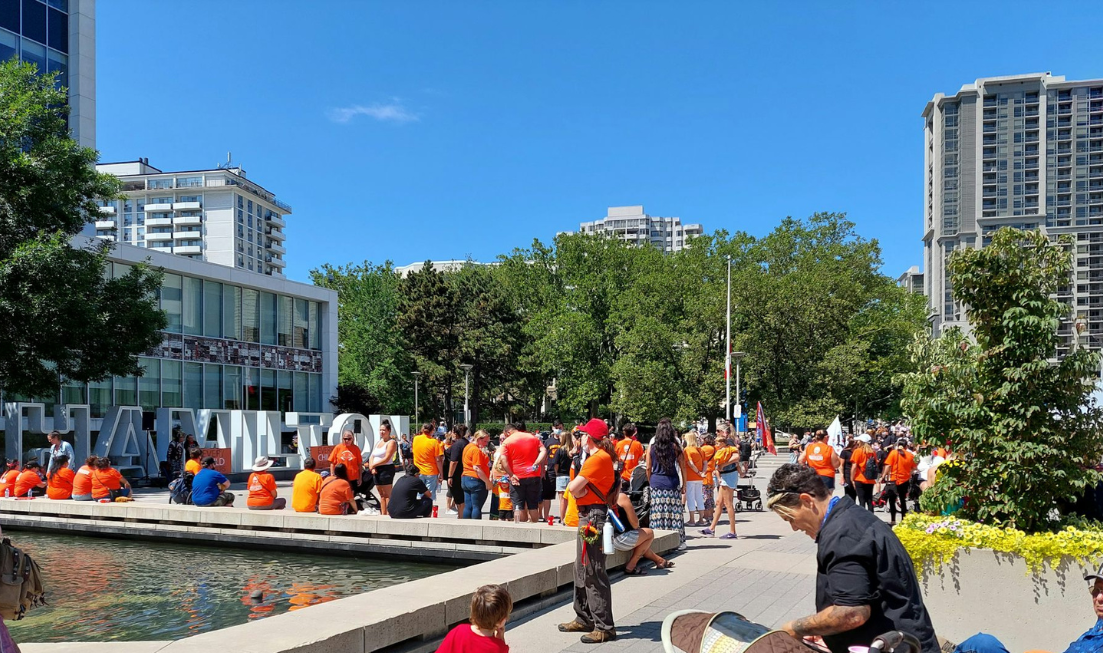 A large group of people in orange shirts gathered outside Hamilton City Hall.