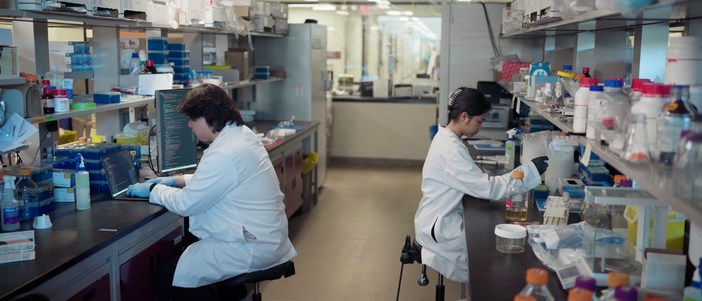 Two people wearing lab coats and working in a lab