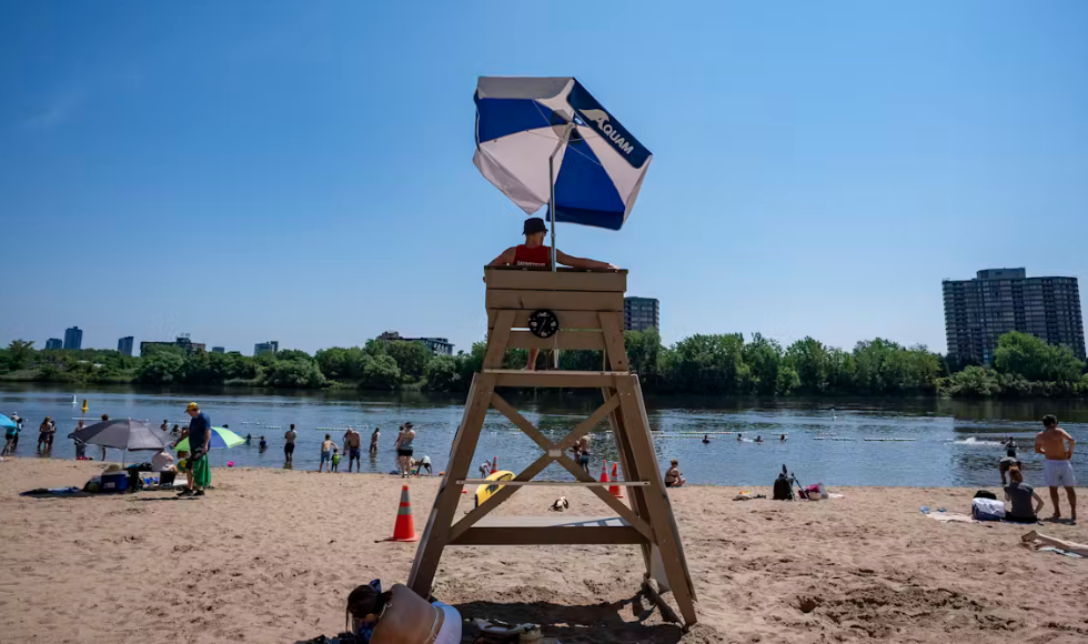 A lifeguard stand at a beach, with several people sunbathing and in the water.