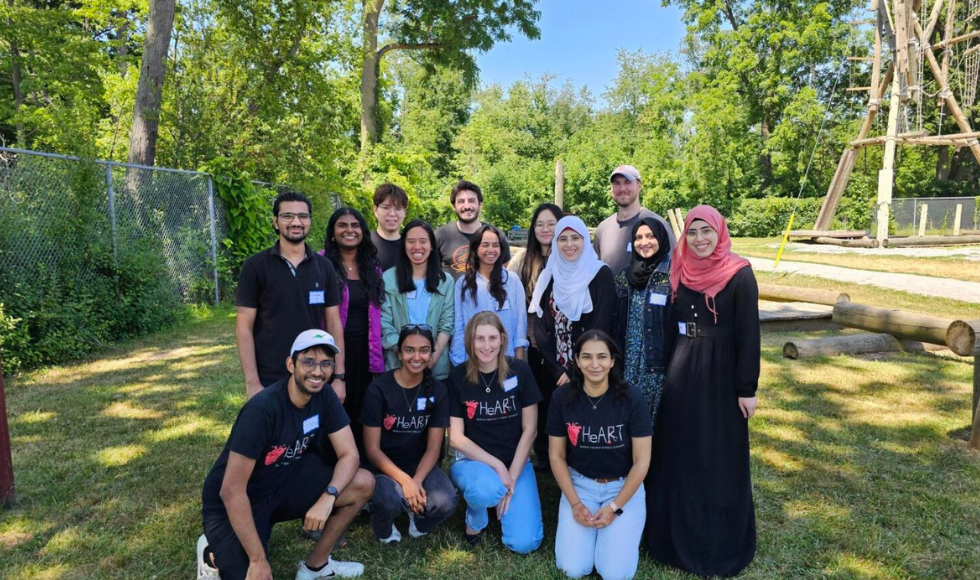 A group of about fifteen people pose together outside.