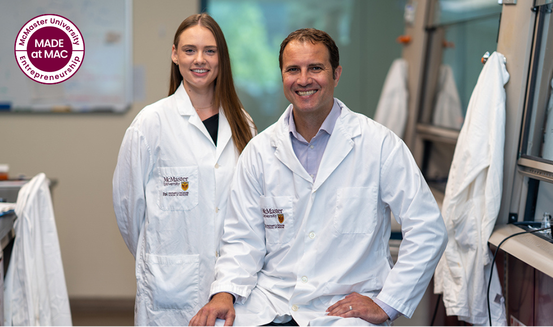 Two smiling researchers in McMaster lab coats, in a lab at McMaster.